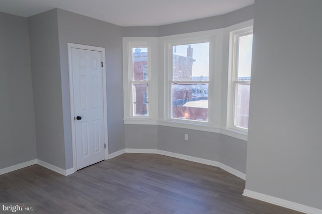 empty room with baseboards and dark wood-style flooring