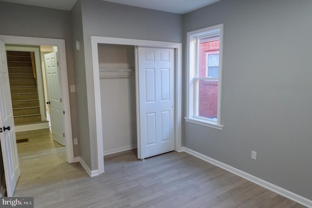 unfurnished bedroom featuring visible vents, light wood-style floors, baseboards, and a closet