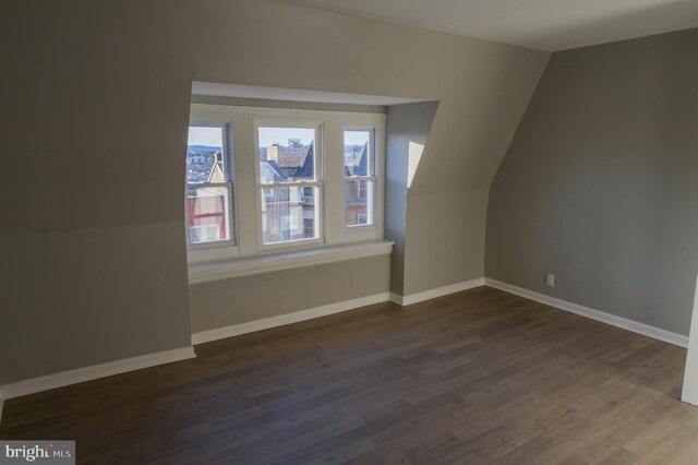 additional living space featuring lofted ceiling, dark wood-style floors, and baseboards