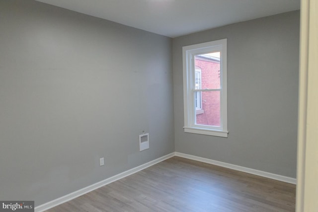 unfurnished room with wood finished floors, visible vents, and baseboards