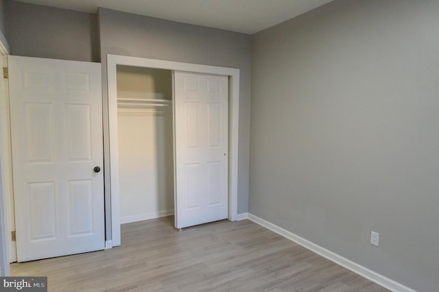 unfurnished bedroom featuring a closet, baseboards, and light wood-style floors