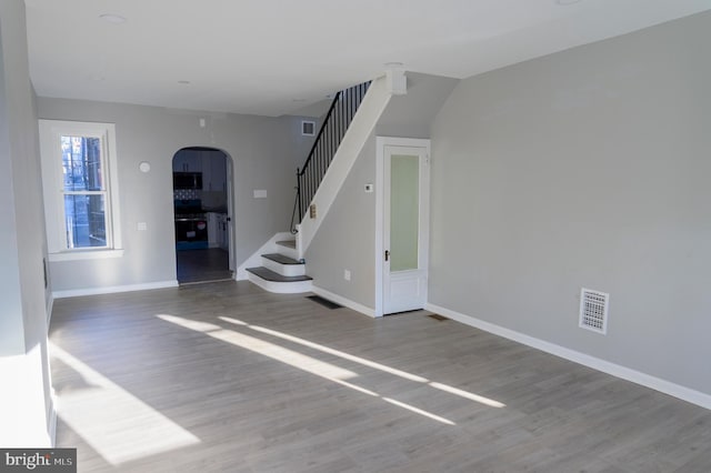 unfurnished living room with stairway, visible vents, and wood finished floors