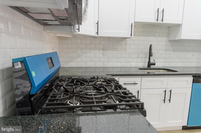 kitchen with dishwashing machine, stainless steel gas range, dark stone counters, a sink, and white cabinetry