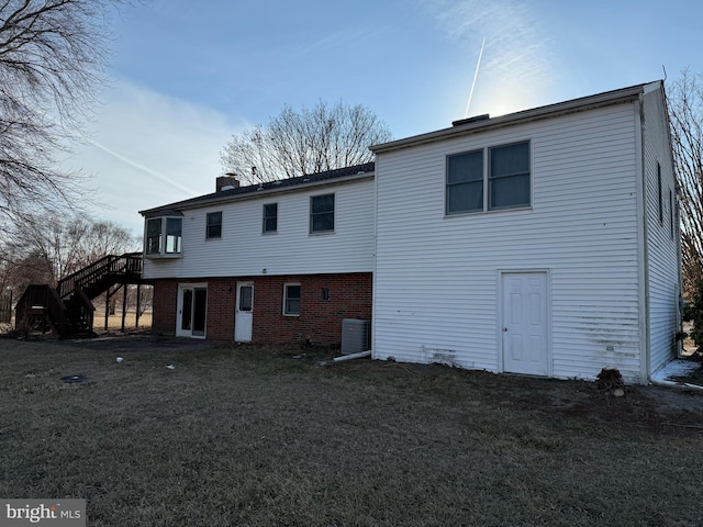 rear view of property with cooling unit and a lawn