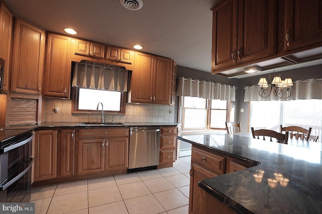 kitchen with light tile patterned flooring, sink, backsplash, dark stone counters, and stainless steel dishwasher