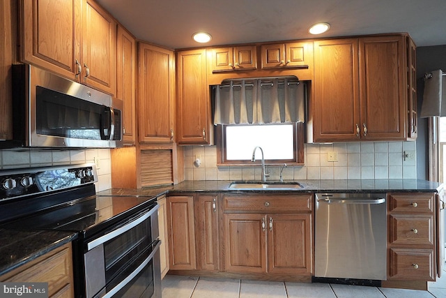 kitchen featuring light tile patterned flooring, sink, dark stone countertops, decorative backsplash, and stainless steel appliances