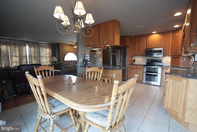 dining room with sink, light tile patterned floors, and a chandelier