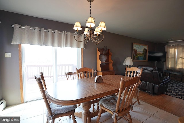 dining area featuring a baseboard heating unit, a chandelier, and light tile patterned floors