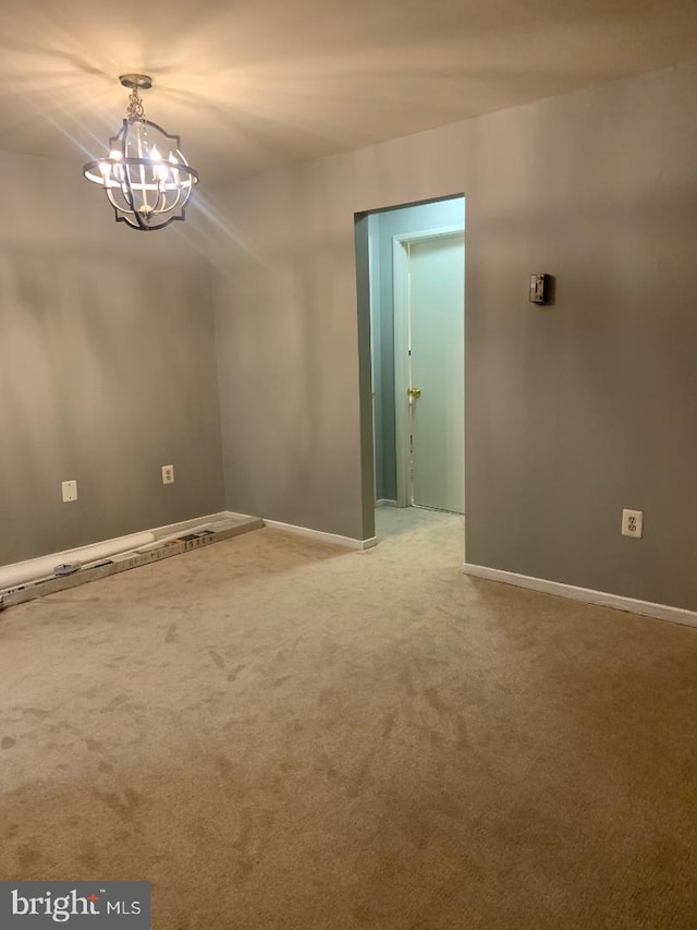 spare room featuring carpet floors and a notable chandelier