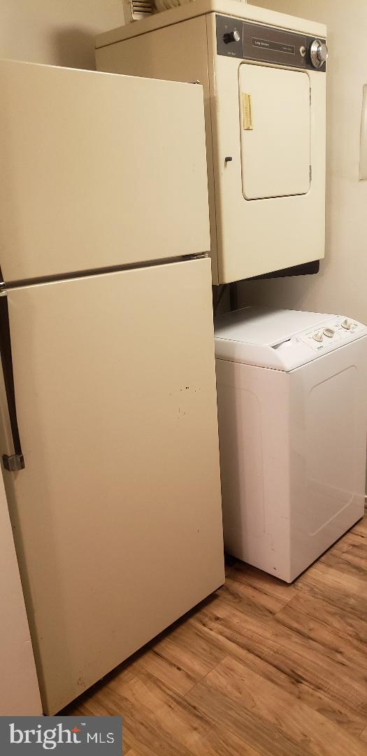 washroom featuring stacked washer / dryer and light hardwood / wood-style floors