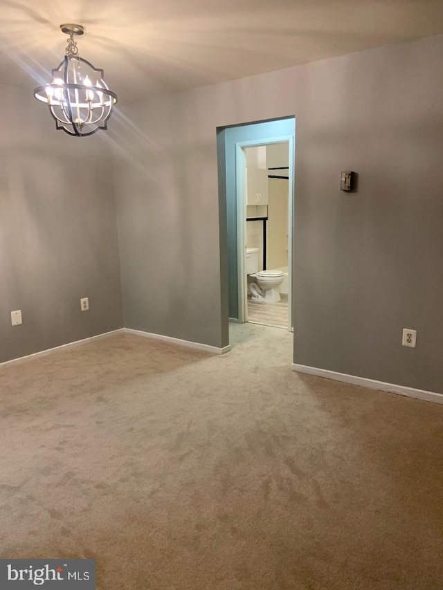 carpeted empty room with a notable chandelier