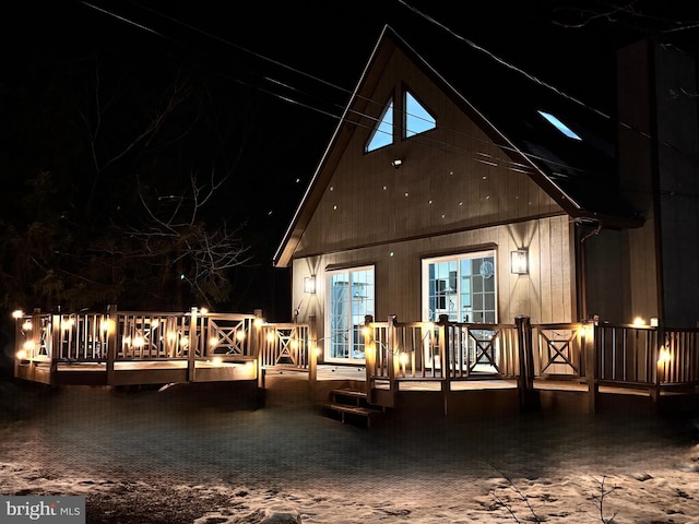 back house at night featuring a wooden deck