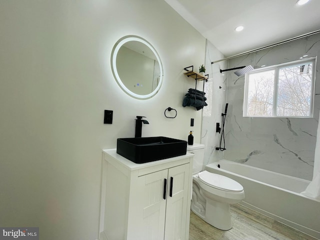 full bathroom featuring tiled shower / bath combo, vanity, hardwood / wood-style floors, and toilet