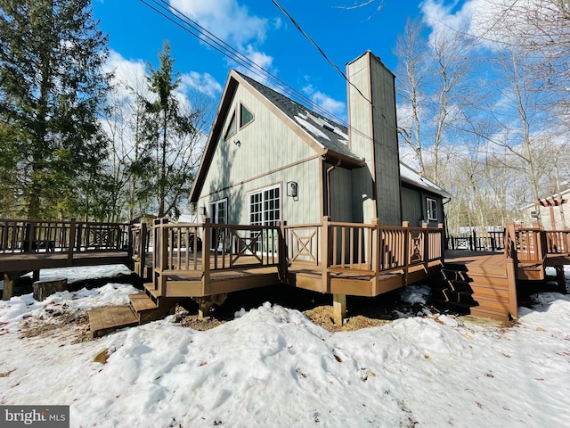 snow covered back of property featuring a deck