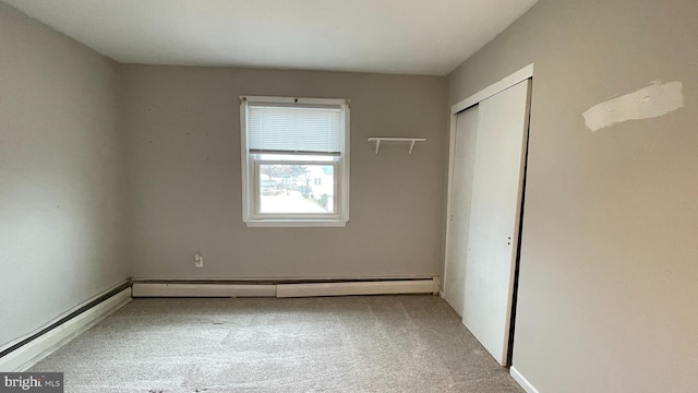 unfurnished bedroom featuring a baseboard heating unit, carpet floors, and a closet