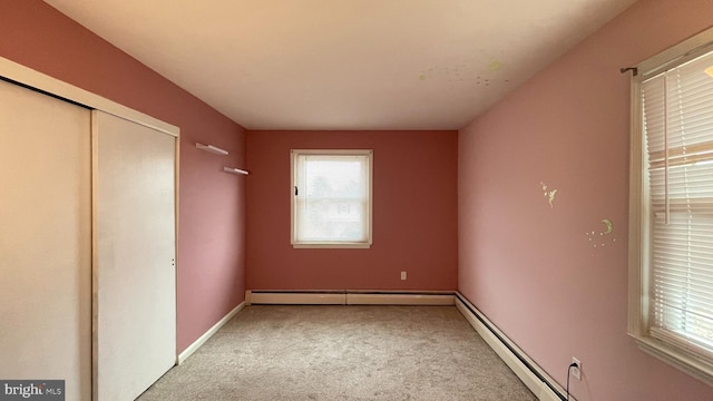 unfurnished bedroom with light carpet, a baseboard heating unit, and a closet