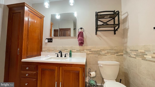 bathroom with vanity, tile walls, and toilet