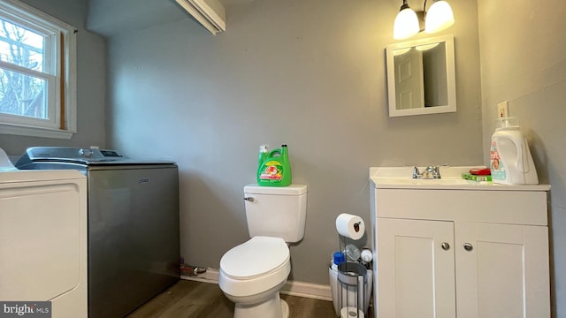 bathroom featuring vanity, wood-type flooring, washing machine and dryer, and toilet