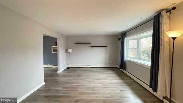 spare room with a baseboard radiator and wood-type flooring