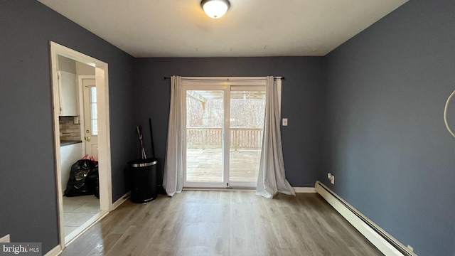 unfurnished room featuring a baseboard heating unit and light hardwood / wood-style flooring