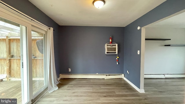 unfurnished room featuring a baseboard radiator, a wall unit AC, and wood-type flooring