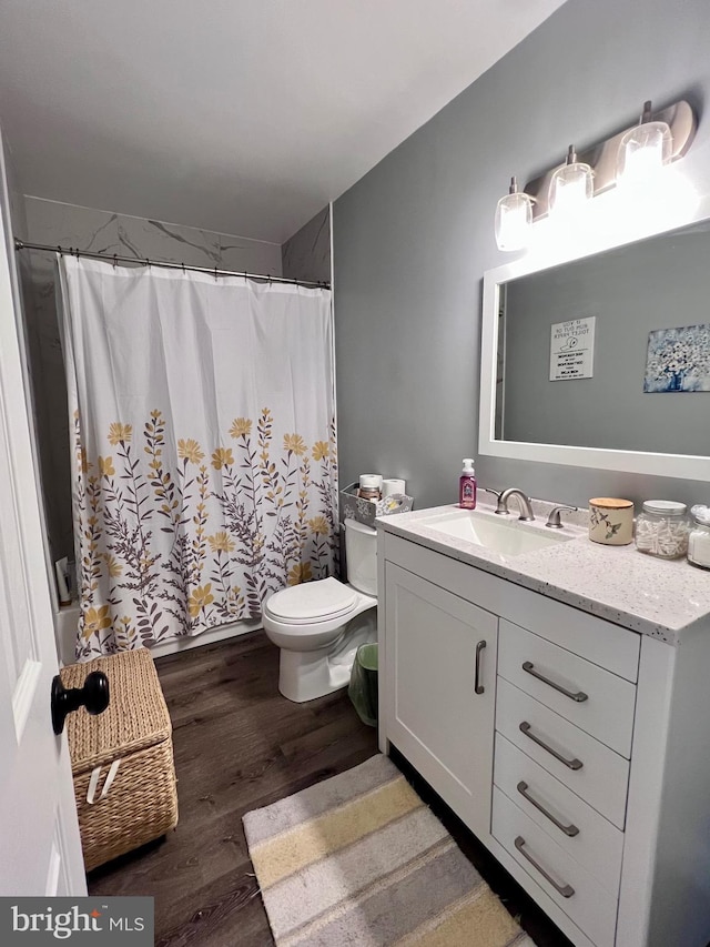 bathroom featuring vanity, curtained shower, wood-type flooring, and toilet