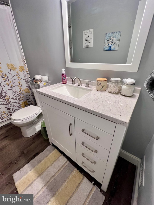 bathroom with hardwood / wood-style flooring, vanity, and toilet