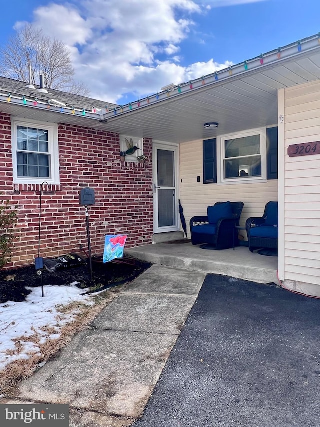 snow covered property entrance with a patio