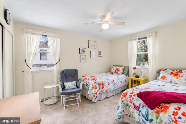 carpeted bedroom featuring multiple windows, a closet, and ceiling fan