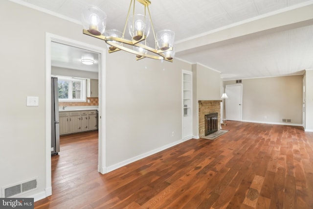 unfurnished living room featuring crown molding, wood finished floors, a chandelier, and visible vents