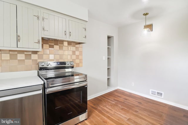kitchen with stainless steel appliances, visible vents, light wood-style floors, decorative backsplash, and light countertops