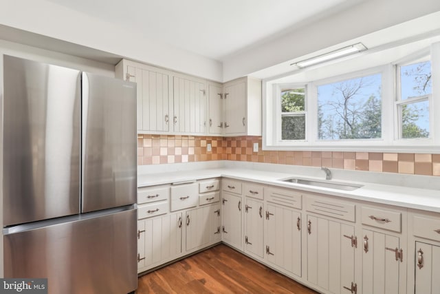 kitchen featuring dark wood-style floors, light countertops, a sink, freestanding refrigerator, and tasteful backsplash