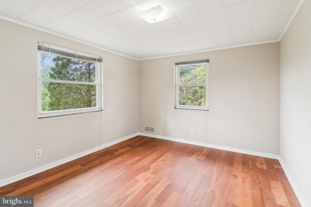 empty room featuring visible vents, ornamental molding, and wood-type flooring
