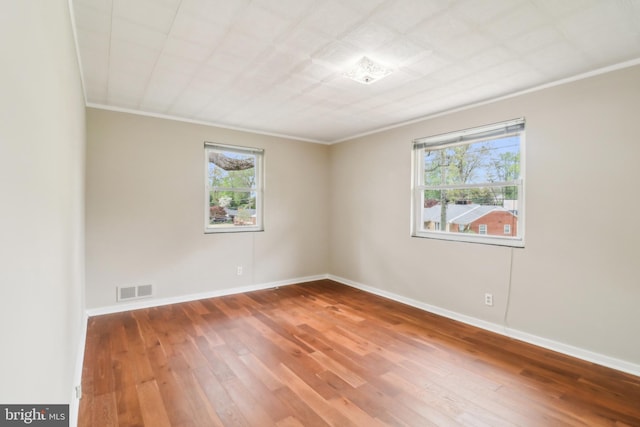 spare room with hardwood / wood-style flooring, a wealth of natural light, crown molding, and baseboards