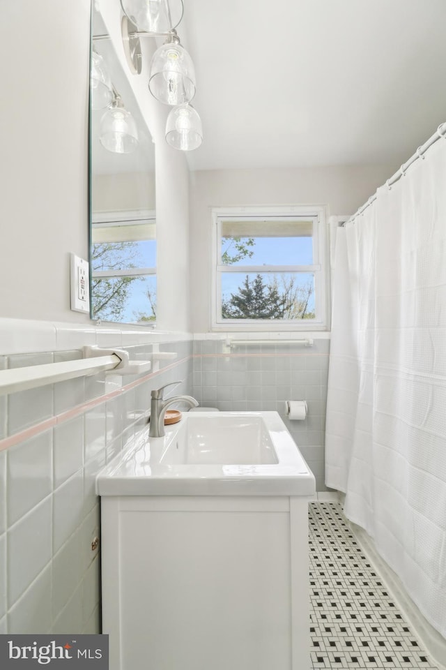 full bathroom with tile patterned floors, a wainscoted wall, tile walls, curtained shower, and vanity