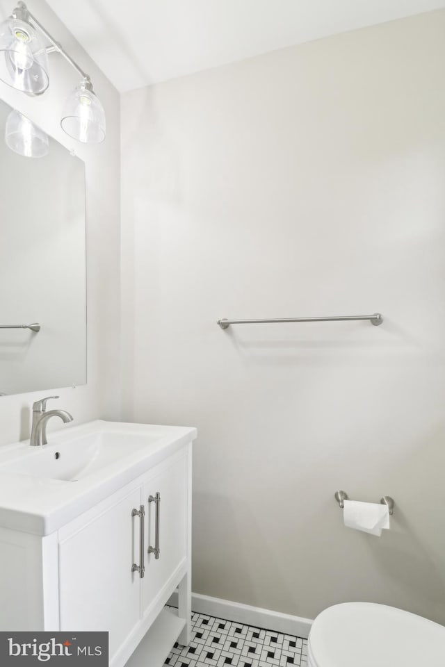 bathroom with toilet, vanity, and baseboards