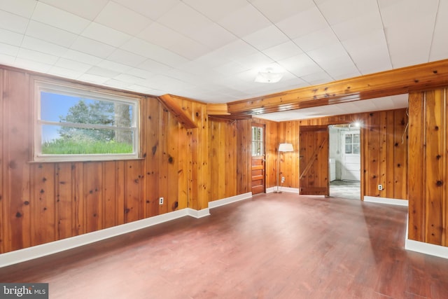basement featuring wood finished floors, wood walls, and baseboards