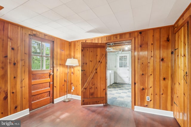 unfurnished room with baseboards, wooden walls, and wood finished floors