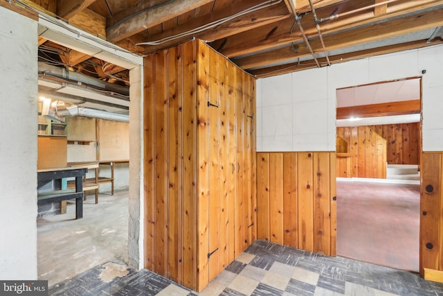 unfinished basement with tile patterned floors and wooden walls