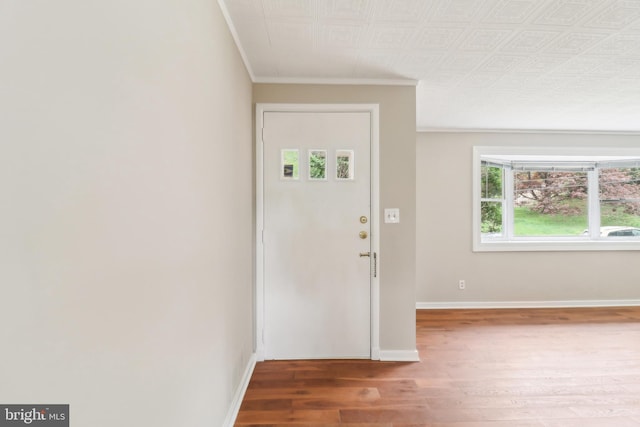 foyer with wood finished floors, crown molding, and baseboards