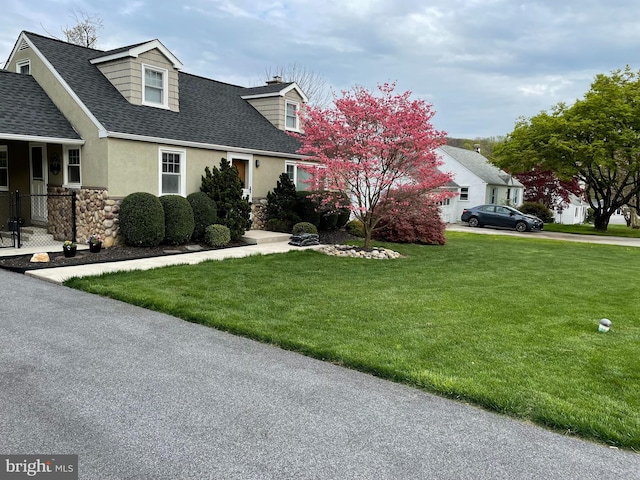 cape cod house with a front lawn