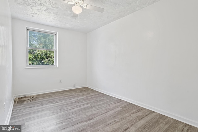 empty room featuring ceiling fan, light hardwood / wood-style floors, and a textured ceiling