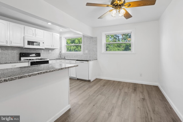 kitchen featuring backsplash, white cabinets, white appliances, and light hardwood / wood-style floors