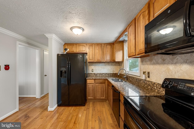 kitchen with sink, dark stone countertops, backsplash, black appliances, and light wood-type flooring