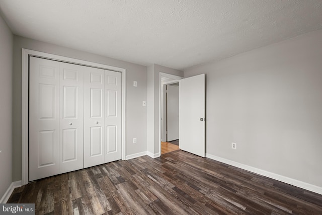 unfurnished bedroom featuring dark hardwood / wood-style floors, a textured ceiling, and a closet