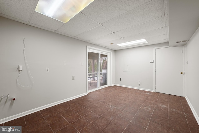 tiled spare room featuring a paneled ceiling