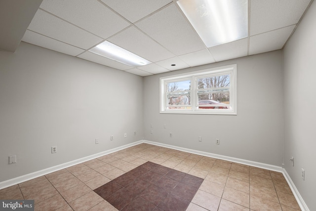 tiled spare room featuring a paneled ceiling