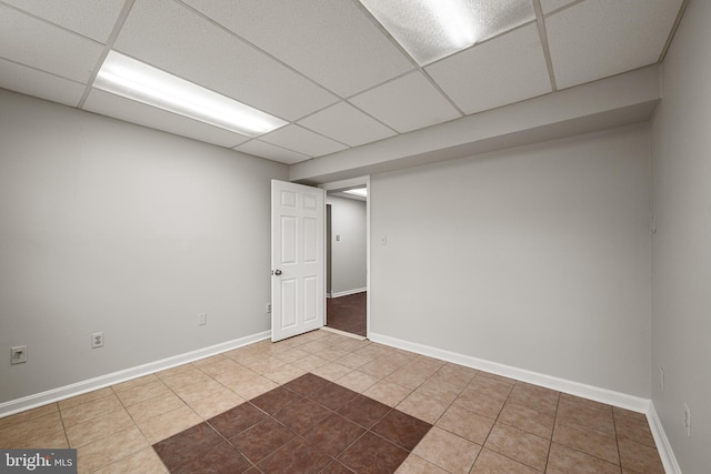 basement featuring a paneled ceiling and tile patterned flooring