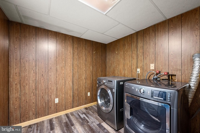 laundry room featuring wooden walls, dark hardwood / wood-style floors, and washer and dryer