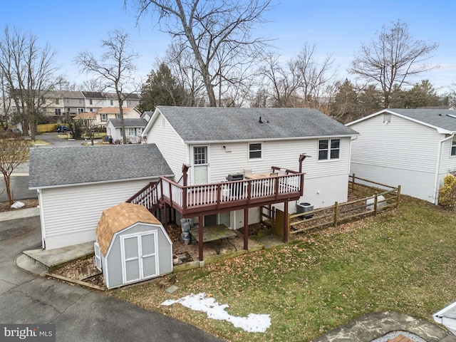 back of property featuring a storage unit, a deck, and a lawn